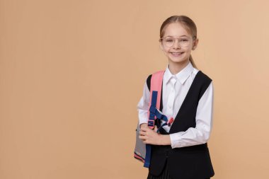 Kahverengi arka planda sırt çantalı gülümseyen kız. Metin için boşluk