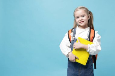 Sırt çantası ve açık mavi arka plan kitabı olan tatlı bir kız öğrenci. Metin için boşluk