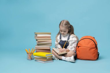Sırt çantası ve açık mavi arka plan kitapları olan liseli kız.