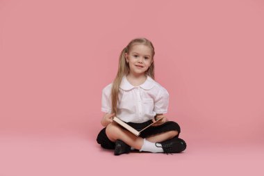Pembe arka plan kitabı olan tatlı bir kız öğrenci.