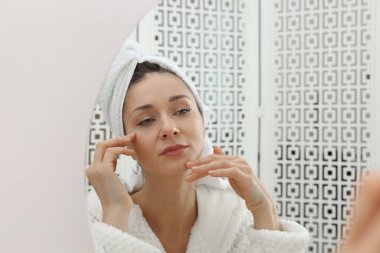 Spa günü. İçerideki aynanın yanında bornozlu güzel bir kadın.