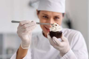 Şekerci, mutfakta bir parça çikolatayla kek dekore ediyor, seçici odaklı.