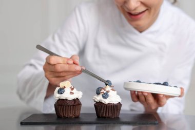 Şekerci, masayı yaban mersinli kek ile dekore ediyor.