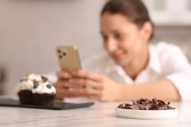 Şekerci masada lezzetli keklerin fotoğrafını çekiyor, seçici odaklı.