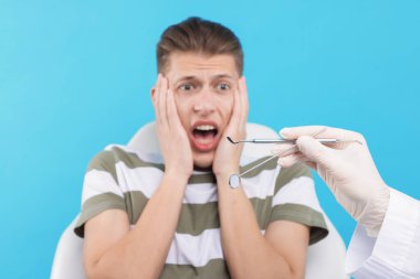 Korkan adamın açık mavi arka planda dişçiyle randevusu var, seçici odak