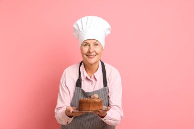 Pembe arka planda pastası olan profesyonel bir pastacı.