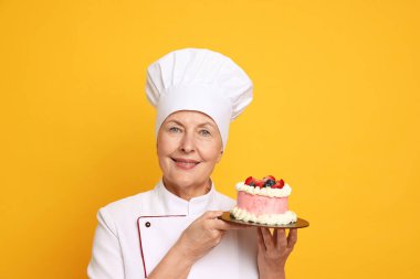 Turuncu arka planda pastası olan profesyonel pasta şefi.