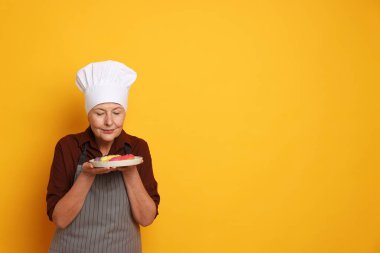 Turuncu arka planda eklerleri olan profesyonel bir şekerci. Metin için boşluk