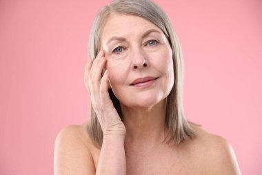 Pembe arka planda sağlıklı ciltli bir kadın.