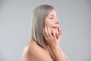 Gri arka planda sağlıklı ciltli bir kadın.