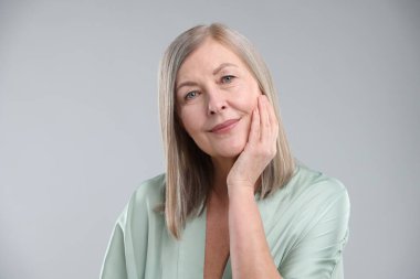 Gri arka planda sağlıklı ciltli bir kadın.