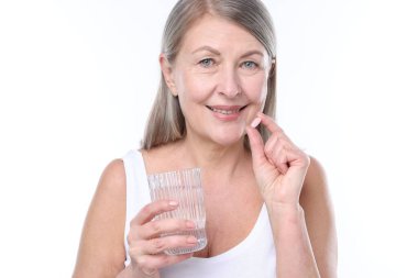 Kollajen hapı ve beyaz arka planda bir bardak suyla gülümseyen kadın.