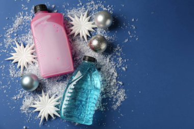 Plastik şişelerde antifriz, takılar, dekoratif kar taneleri ve mavi arka planda buz, düz bir zemin. Metin için boşluk