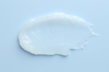 Açık mavi arkaplanda nemlendirici dudak kremi, üst görünüm