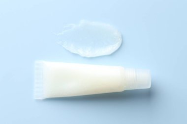 Açık mavi arkaplanda nemlendirici dudak kremi ve tüp, üst görünüm