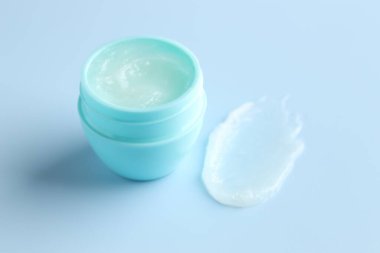 Açık mavi arkaplanda nemlendirici dudak kremi ve kavanoz