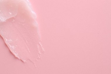 Pembe arka planda nemlendirici dudak kremi, üst manzara. Metin için boşluk