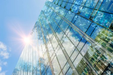 Modern gökdelen ve yemyeşil ağaçlar mavi gökyüzüne karşı, çift pozlama. Düşük açı görünümü