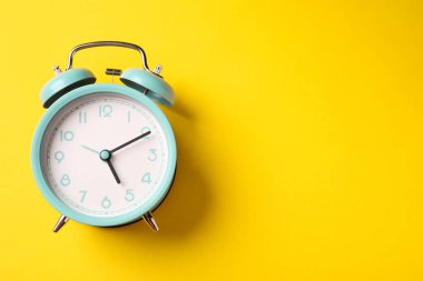 Sarı arka planda turkuaz alarm saati, üst manzara. Metin için boşluk