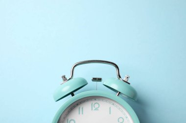 Açık mavi arka planda turkuaz alarm saati, üst manzara. Metin için boşluk