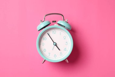 Pembe arka planda turkuaz alarm saati, üst görünüm