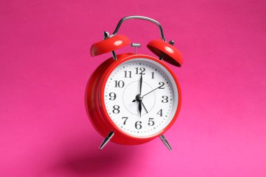 Parlak pembe arka planda kırmızı alarmlı saat