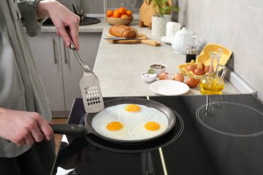 Kadın tavada yumurta pişiriyor. Kapalı mekanda, yakın plan.