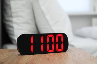 Dijital alarm saat 11 'de kapalı bir odada, komodinin yanında.