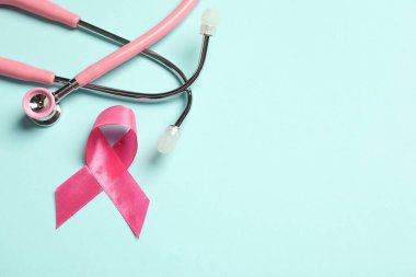 Göğüs kanseri farkındalığı. Açık mavi arka planda pembe kurdele ve steteskop. Metin için boşluk
