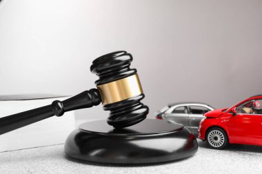 Motorlu taşıt kazası yasası. Gri arkaplanda Gavel ve araba modelleri