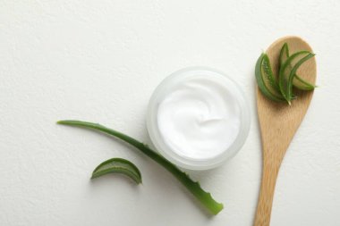 Aloe vera özütüyle nemlendirici krem ve beyaz desenli arka planda yapraklar.