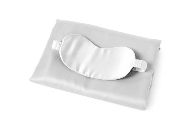 Beyaz arka planda ipek çarşaflar ve uyku maskesi.