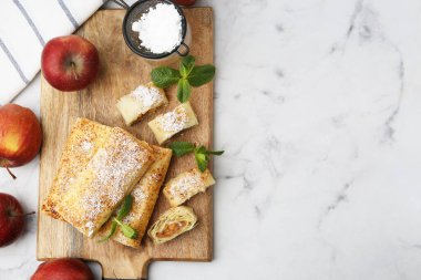 Pudra şekerli, meyveli ve nane şekerli elmalı turtalar beyaz mermer masada, düz yerde. Metin için boşluk