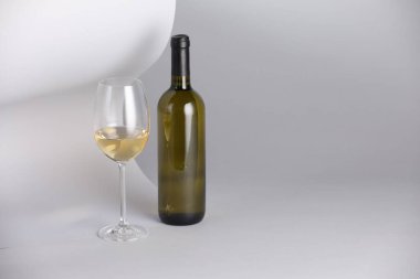 Açık gri arka planda bir şişe ve bir bardak lezzetli şarap. Metin için boşluk