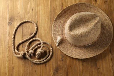 Pamuk ipten yapılmış kement ve ahşap arka planda hasır şapka, düz yatıyordu.