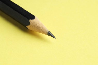 Sarı arka planda keskin bir grafit kalem, yakın plan. Metin için boşluk