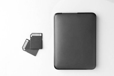 Beyaz arkaplandaki harici sabit disk ve SD hafıza kartları, düz konum
