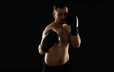 Siyah arka planda dövüşen boks eldivenli adam.