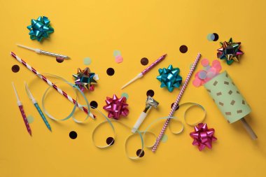 Turuncu arka planda konfeti, hava üfleyici ve şenlikli bir dekor.