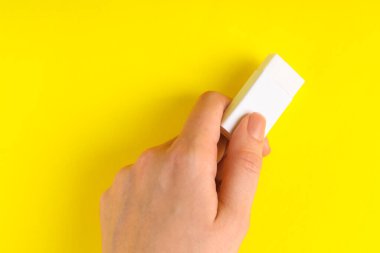 Sarı arkaplanda silgi kullanan kadın, yakın plan