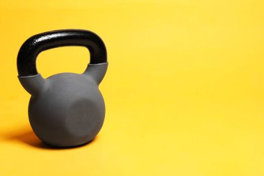 Sarı arka planda ağır bir kettlebell. Metin için boşluk