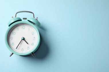Açık mavi arka planda turkuaz alarm saati, üst manzara. Metin için boşluk