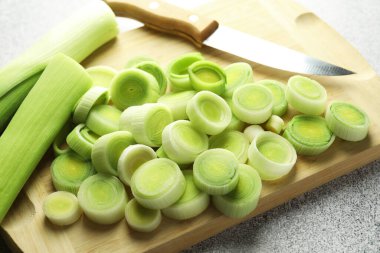 Gri masada doğranmış pırasa ve bıçak, yakın plan.