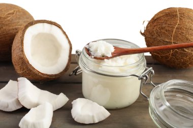 Hindistan cevizleri, pişirme yağı ve kaşık ahşap masada beyaz arka planda