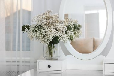 Güzel çigila çiçekleri ve okaliptüs dalları vazoda aynanın yanındaki tuvalet masasında.