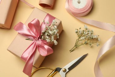 Çiçekçi. Bej arka planda kutular, çiçekler, kurdele ve makas, düz uzanma