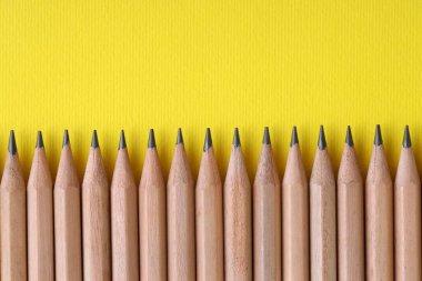 Sarı arka planda bir sürü kalem, üst manzara. Metin için boşluk