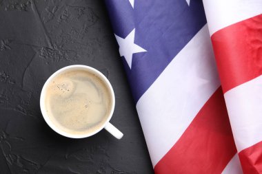 Bir fincan kahve ve siyah masa üzerinde Amerikan bayrağı.