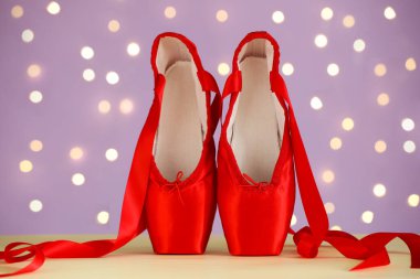 Bulanık ışıklara karşı bej masada bir çift şık sivri ayakkabı.