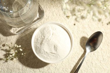 Kolajen tozu kase, kaşık, bir bardak su ve çingene dalları açık dokulu masa, düz yatıyordu.